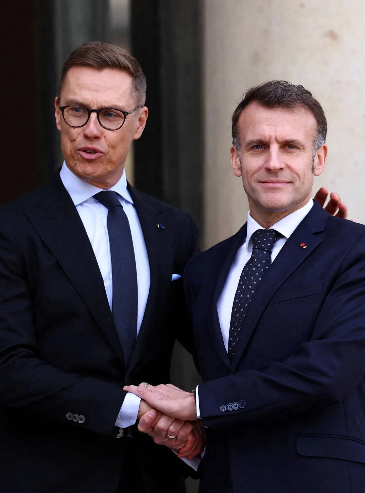الرئيس الفرنسي إيمانويل ماكرون مصافحاً نظيره الفنلندي ألكسندر ستوب عند مدخل قصر الإليزيه في باريس الاثنين (رويترز)