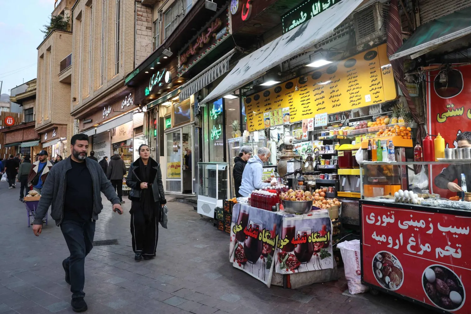Iranians walk past shops selling food ahead of Iftar, the Ramadan fast-breaking meal, in northern Tehran on February 23, 2026. (AFP)