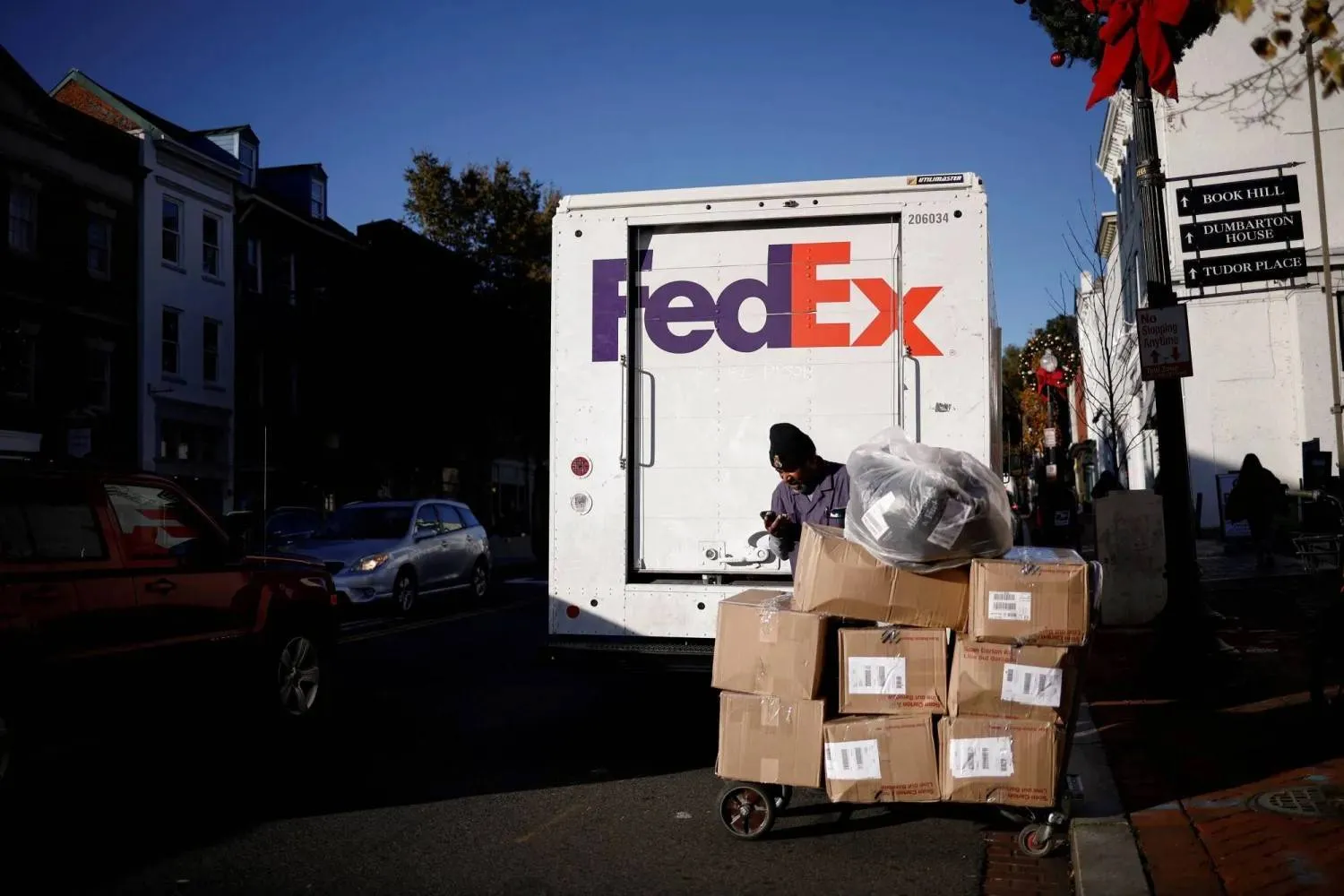 A driver of FedEx stands with packages near a delivery truck during Black Friday preparations in the Georgetown neighborhood of Washington, US, November 26, 2024. REUTERS/Benoit Tessier/File Photo 