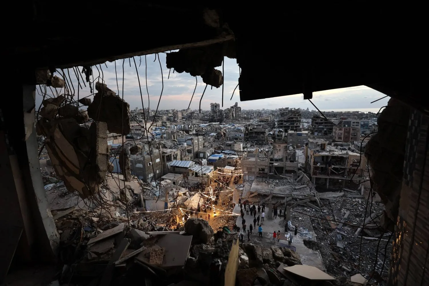 نازحون يتجمعون لتناول وجبة إفطار رمضان وسط أنقاض المباني المدمرة في مخيم جباليا للاجئين شمال قطاع غزة (أ.ف.ب)