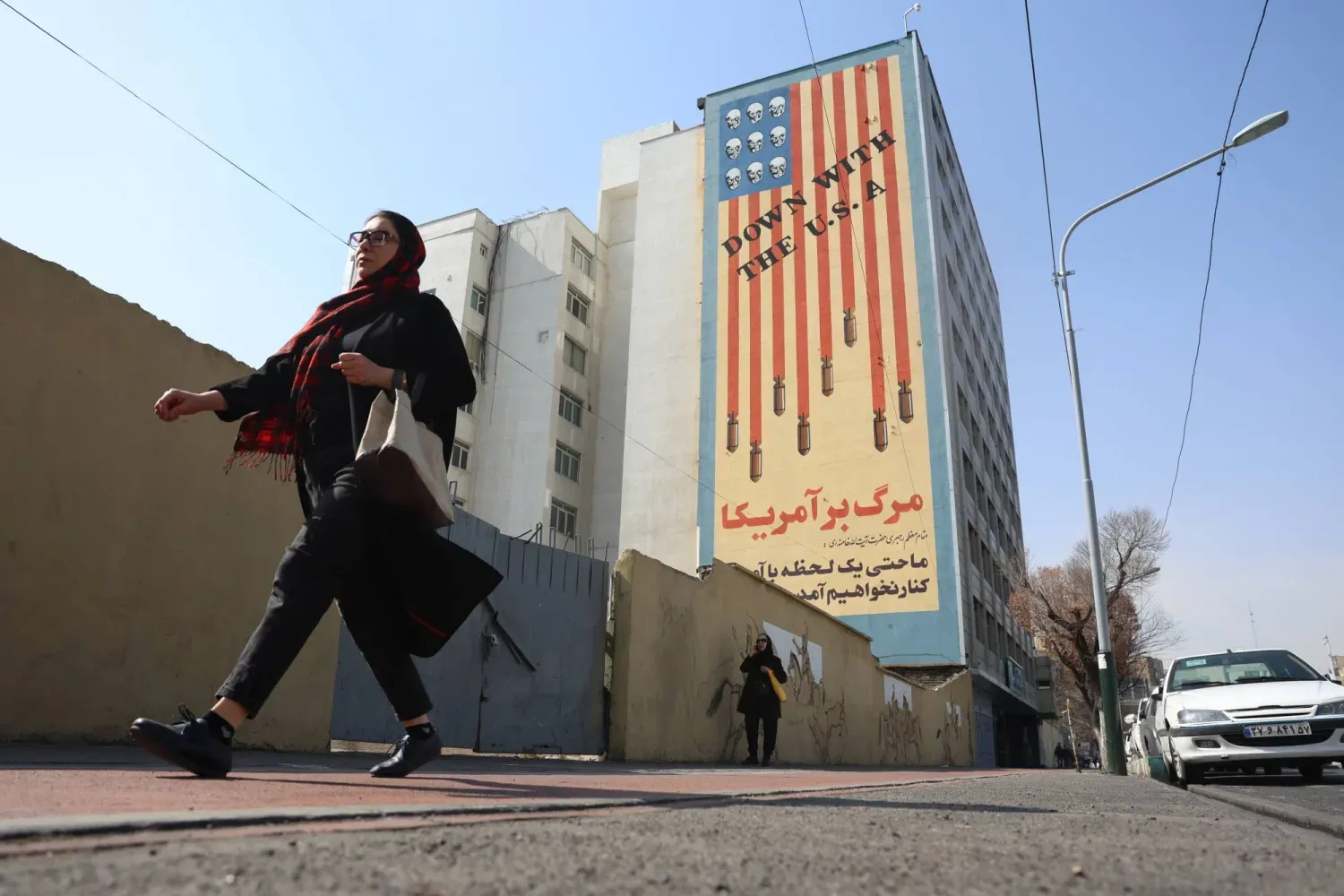 Tahran'da bir İranlı kadın, Amerikan karşıtı bir duvar resminin önünden geçiyor (EPA)