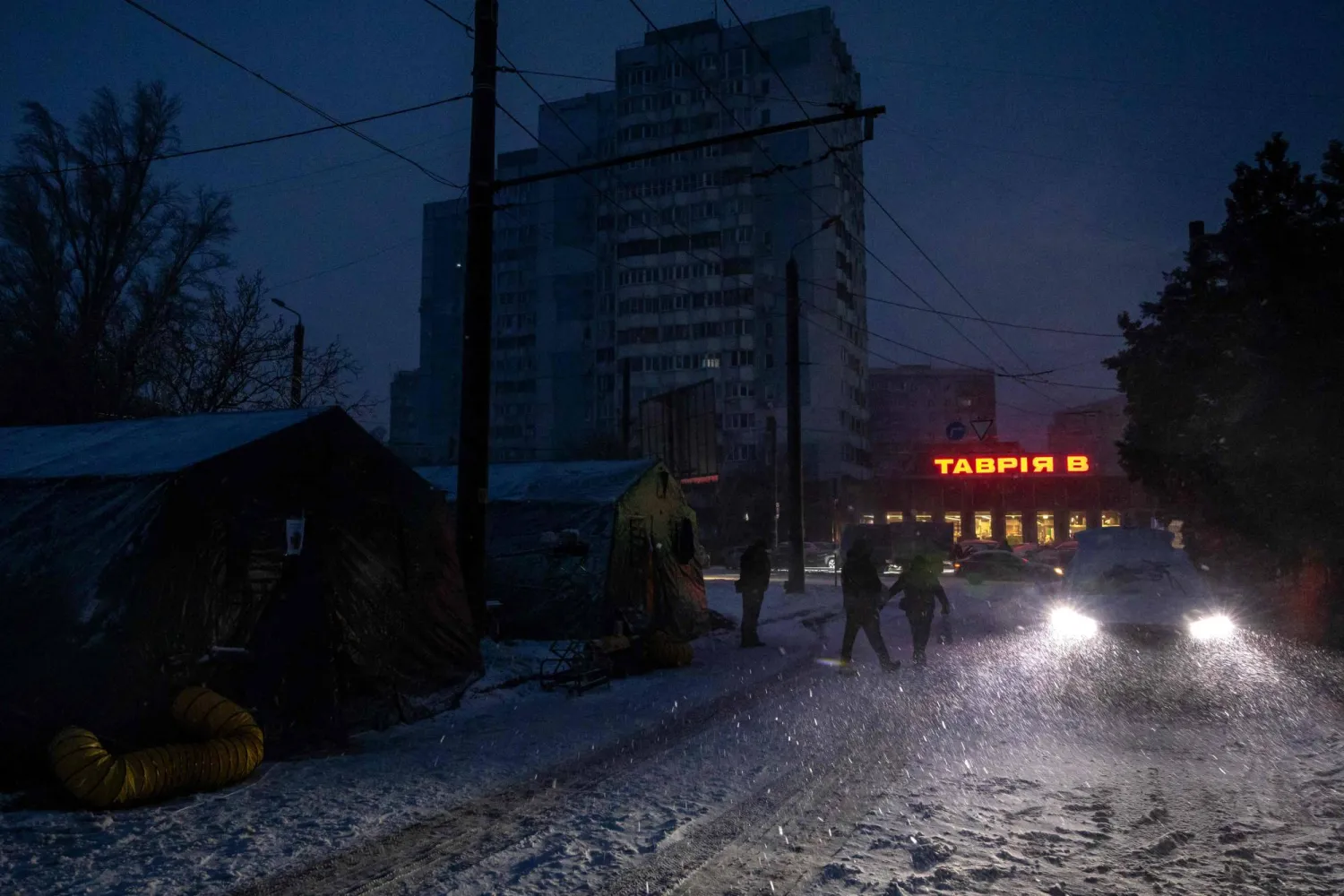 Local residents walk past heated tents during a power outage in Odesa on February 18, 2026, amid the Russian invasion of Ukraine. (AFP)