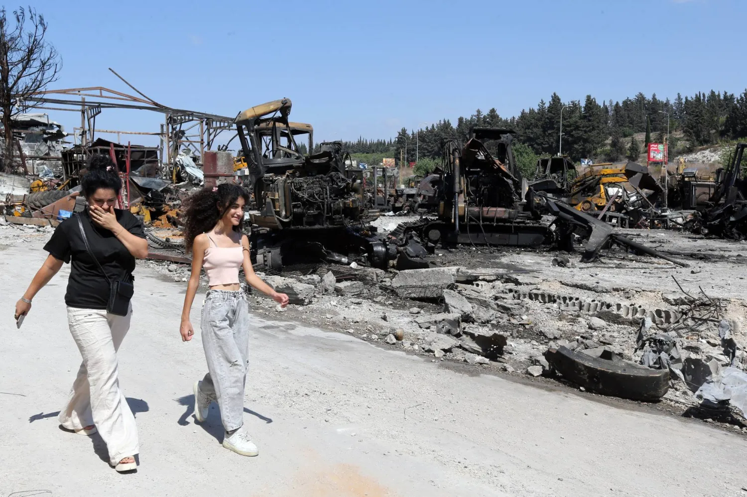 لبنانيتان تسيران قرب موقع استهدفته إسرائيل كان لباحة صيانة جرافات ببلدة أنصار جنوب لبنان خلال سبتمبر 2025 (أرشيفية - إ.ب.أ)