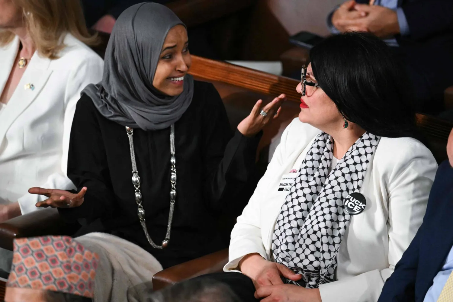 (L/R) US Representatives Ilhan Omar, Democrat from Minnesota, and Rashida Tlaib, Democrat from Michigan, look on as President Donald Trump delivers the State of the Union address in the House Chamber of the US Capitol in Washington, DC, on February 24, 2026. (Photo by Mandel NGAN / AFP)