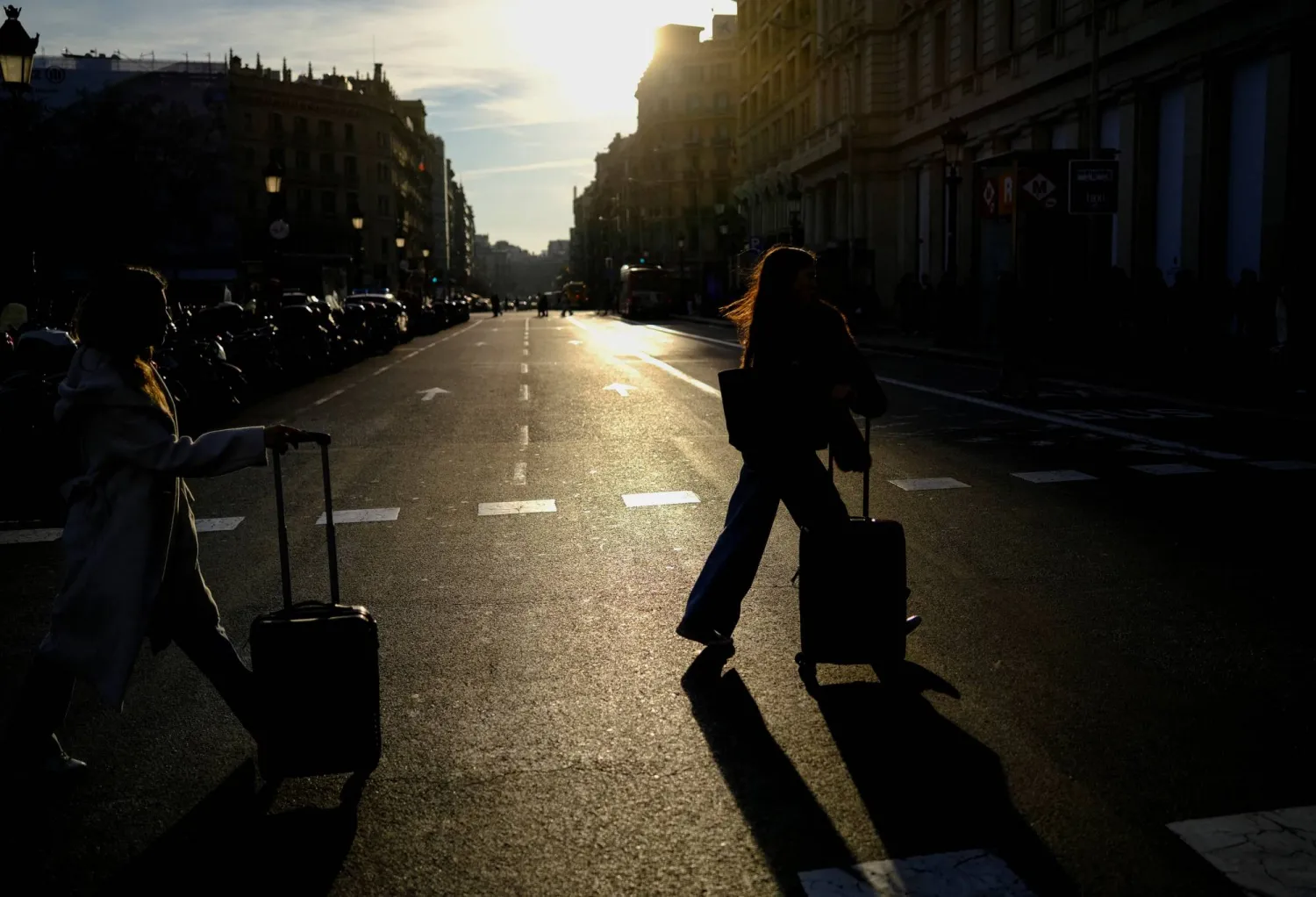 سياح يجرون أمتعتهم عند وصولهم إلى ساحة كاتالونيا في برشلونة (رويترز)