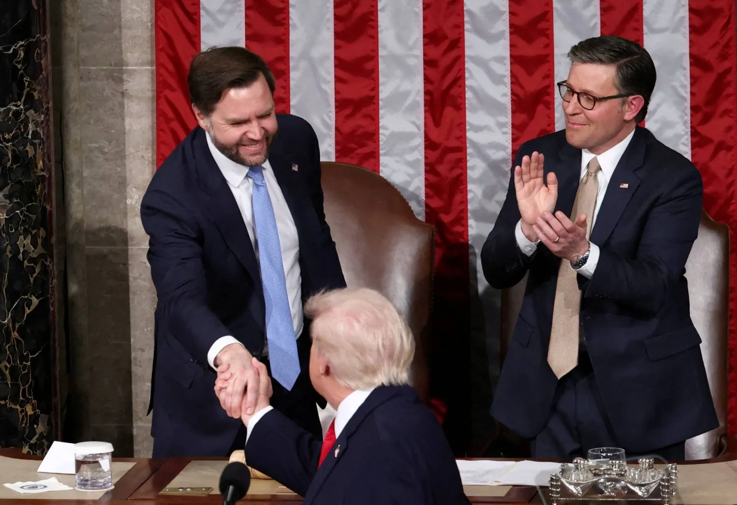 FILE PHOTO: US President Donald Trump shakes hands with US Vice President J.D. Vance as US House Speaker Mike Johnson (R-LA) applauds during Trump's State of the Union Address in the House Chamber at the US Capitol in Washington, D.C., US, February 24, 2026.  REUTERS/KEVIN LAMARQUE/File Photo
