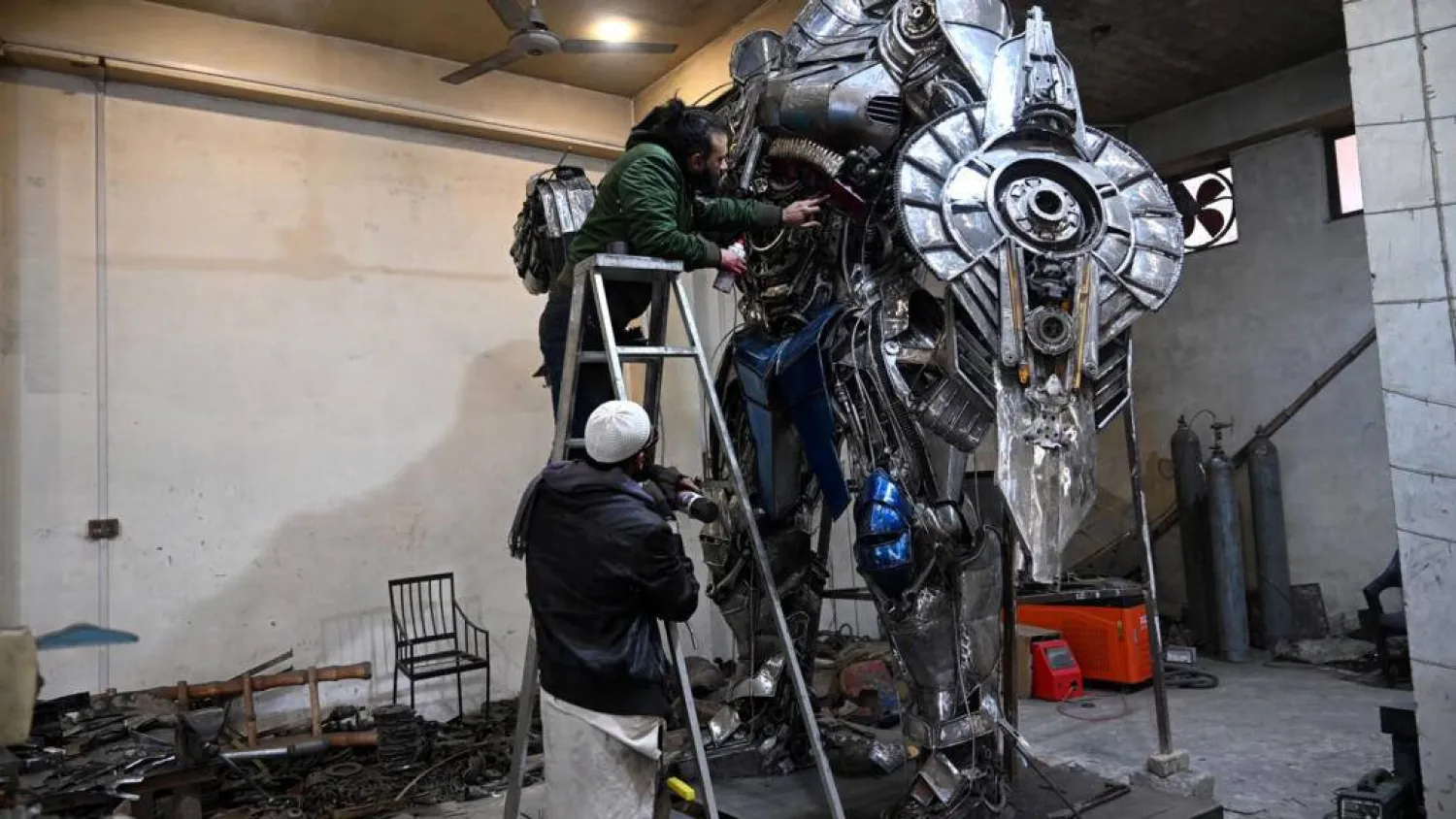 Sculptor Ehtisham Jadoon spray paints a model of Optimus Prime, a film character from Transformers, made from scrap metal at his studio. Farooq NAEEM / AFP
