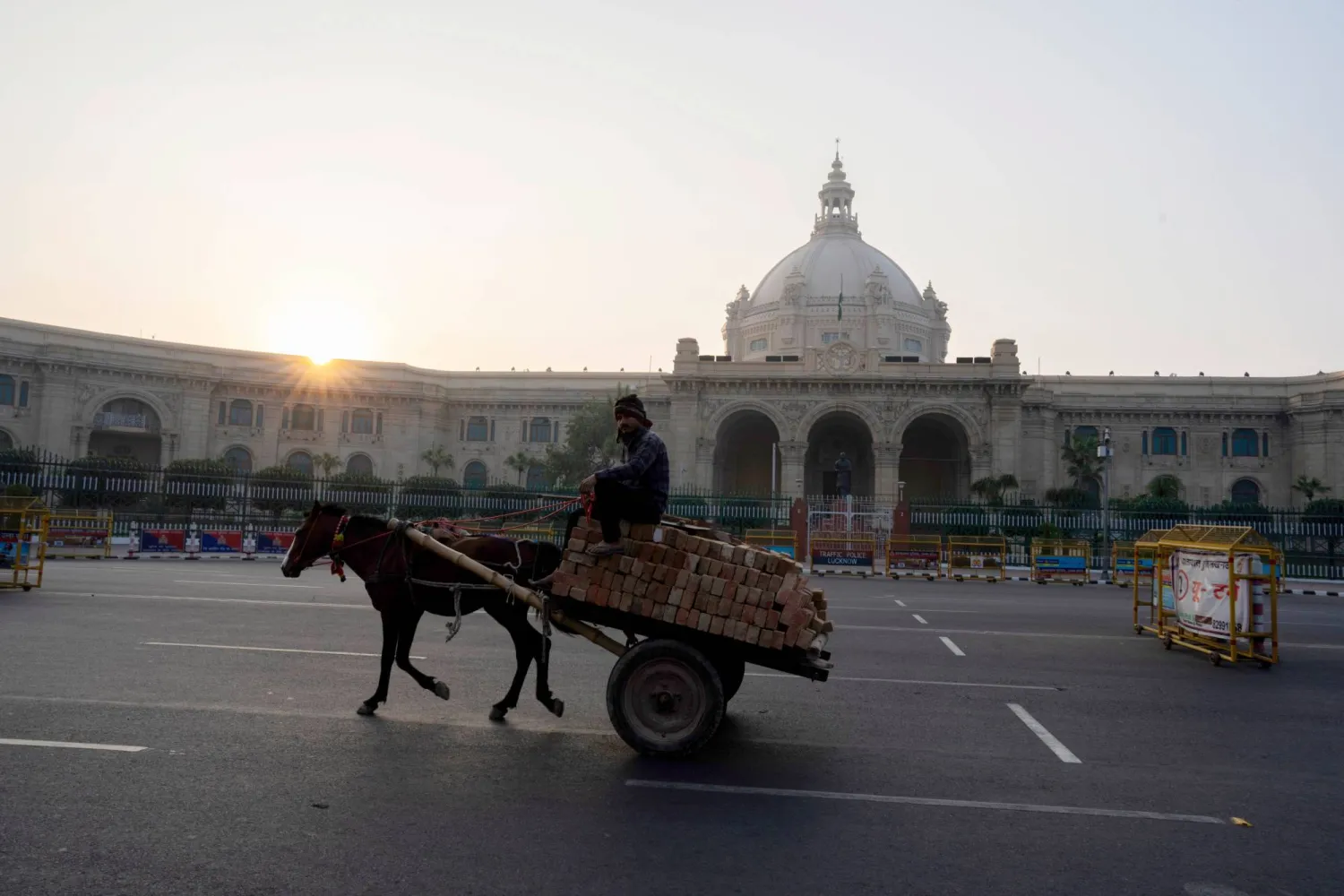 رجل على عربة يجرها حصان يمر في أحد شوارع مدينة لوكنو بولاية براديش الهندية (أ.ب)