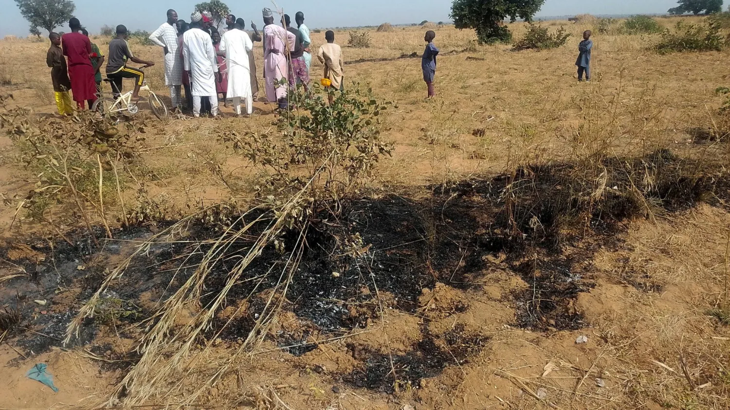 FILE PHOTO: People gather at a site where burnt grass is seen in Jabo village, after US forces had launched a strike against ISIS militants in northwest Nigeria at the request of Nigeria's government, as US President Donald Trump announced on Truth Social on December 25, in Sokoto state, Nigeria, December 26, 2025. REUTERS/Stringer/File Photo 