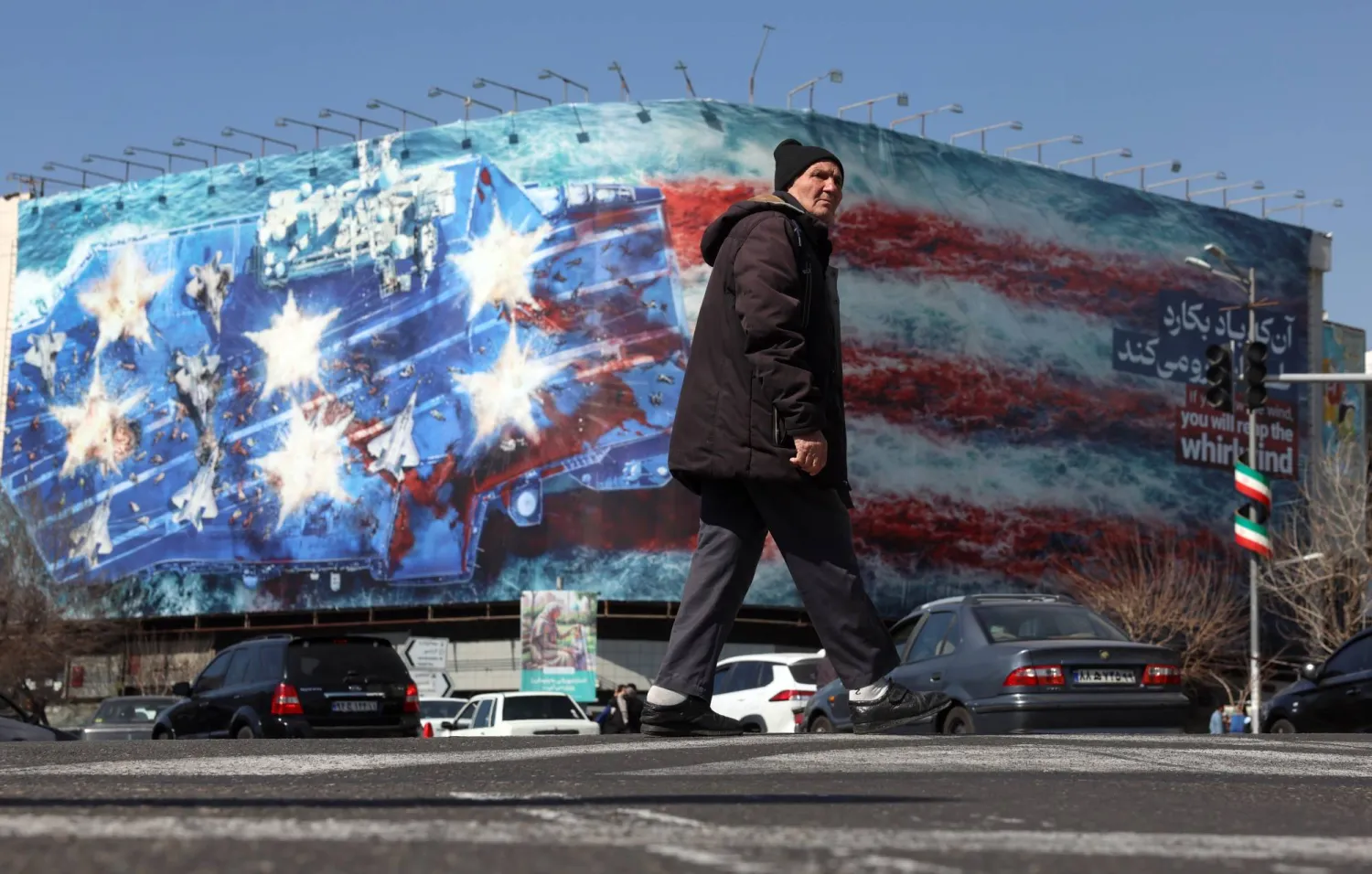 An Iranian man walks near a huge anti-US billboard in a street in Tehran, Iran, 26 February 2026. EPA/ABEDIN TAHERKENAREH