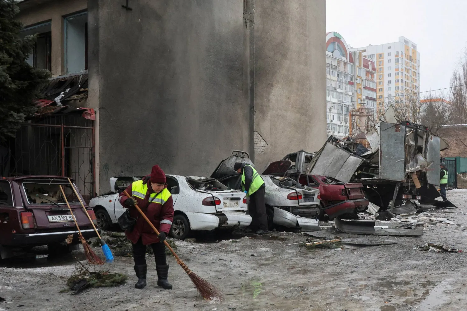 Municipal workers remove debris next to damaged cars outside an apartment building hit by a Russian drone strike on Thursday, amid Russia's attack on Ukraine, in Kharkiv, Ukraine February 26, 2026. REUTERS/Vyacheslav Madiyevskyy 
