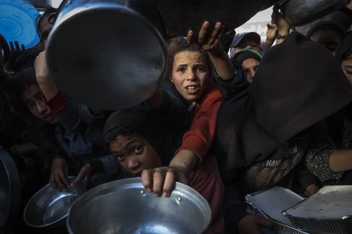 فلسطينيون خلال انتظارهم تلقي الطعام في مطبخ خيري بخان يونس جنوب قطاع غزة (أ.ف.ب)