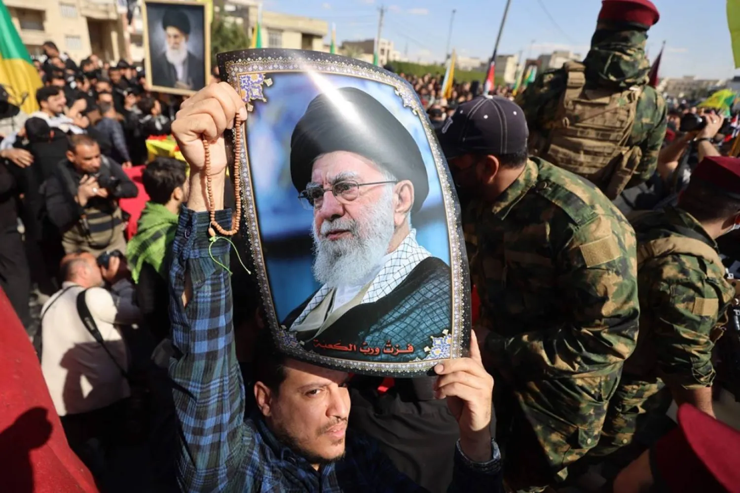 4 Mart'ta hava saldırısında öldürülen Irak Hizbullah Tugayları üyelerinin cenazesi sırasında bir kişinin taşıdığı Hamaney'in bir fotoğrafı (AFP)
