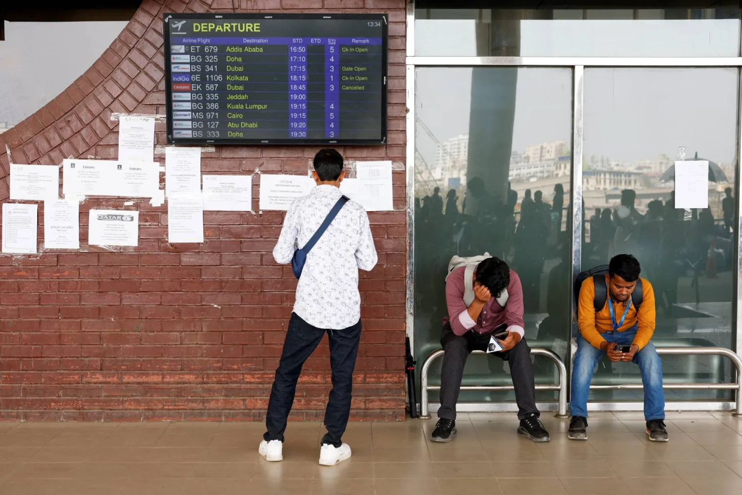 ركاب عالقون ينتظرون في مطار حضرة شاه جلال الدولي بعد إلغاء رحلات جوية إلى دبي والبحرين عقب غارات إيرانية (رويترز)