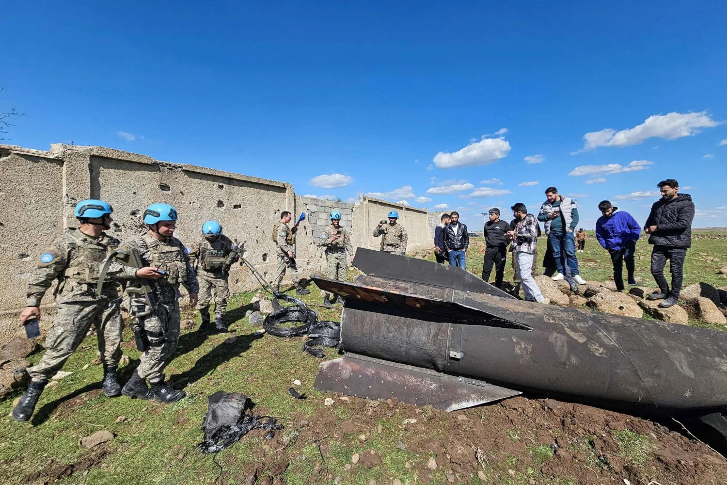 قوات حفظ السلام التابعة للأمم المتحدة ومدنيون قرب حطام صاروخ إيراني اعترضته القوات الإسرائيلية في ريف القنيطرة جنوب سوريا - 28 فبراير (إ.ف.ب)