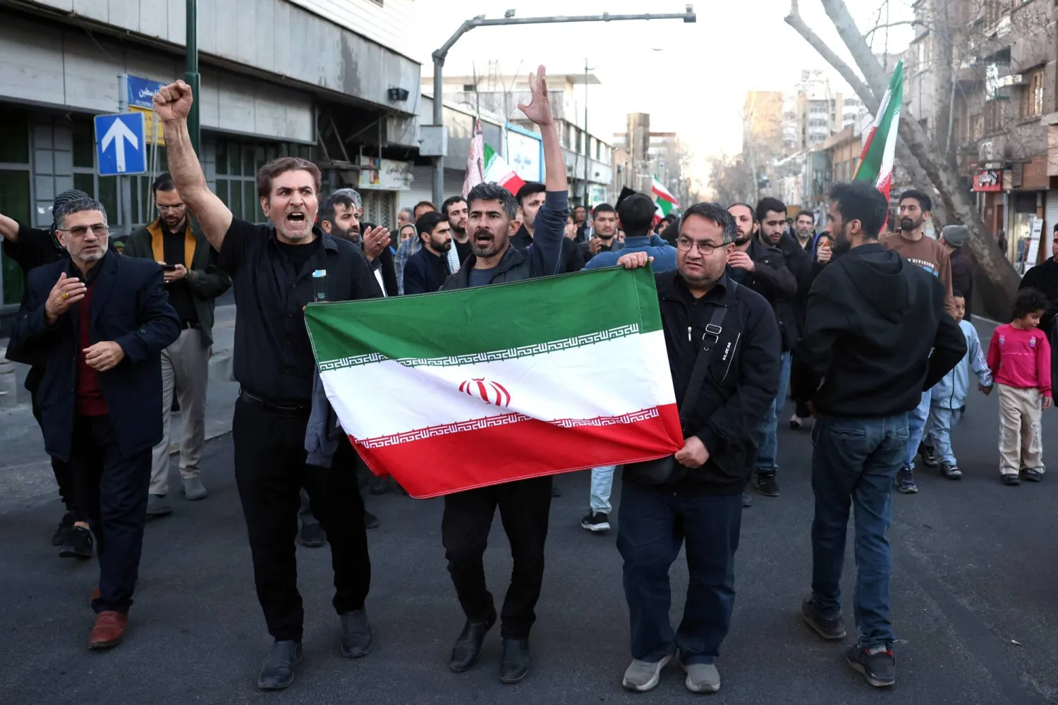 Iranians folding the national flag, march in mourning the day after the assassination of Iran's supreme leader Ali Khamenei, who was killed in joint US and Israeli strikes, in Tehran on March 1, 2026. (AFP)