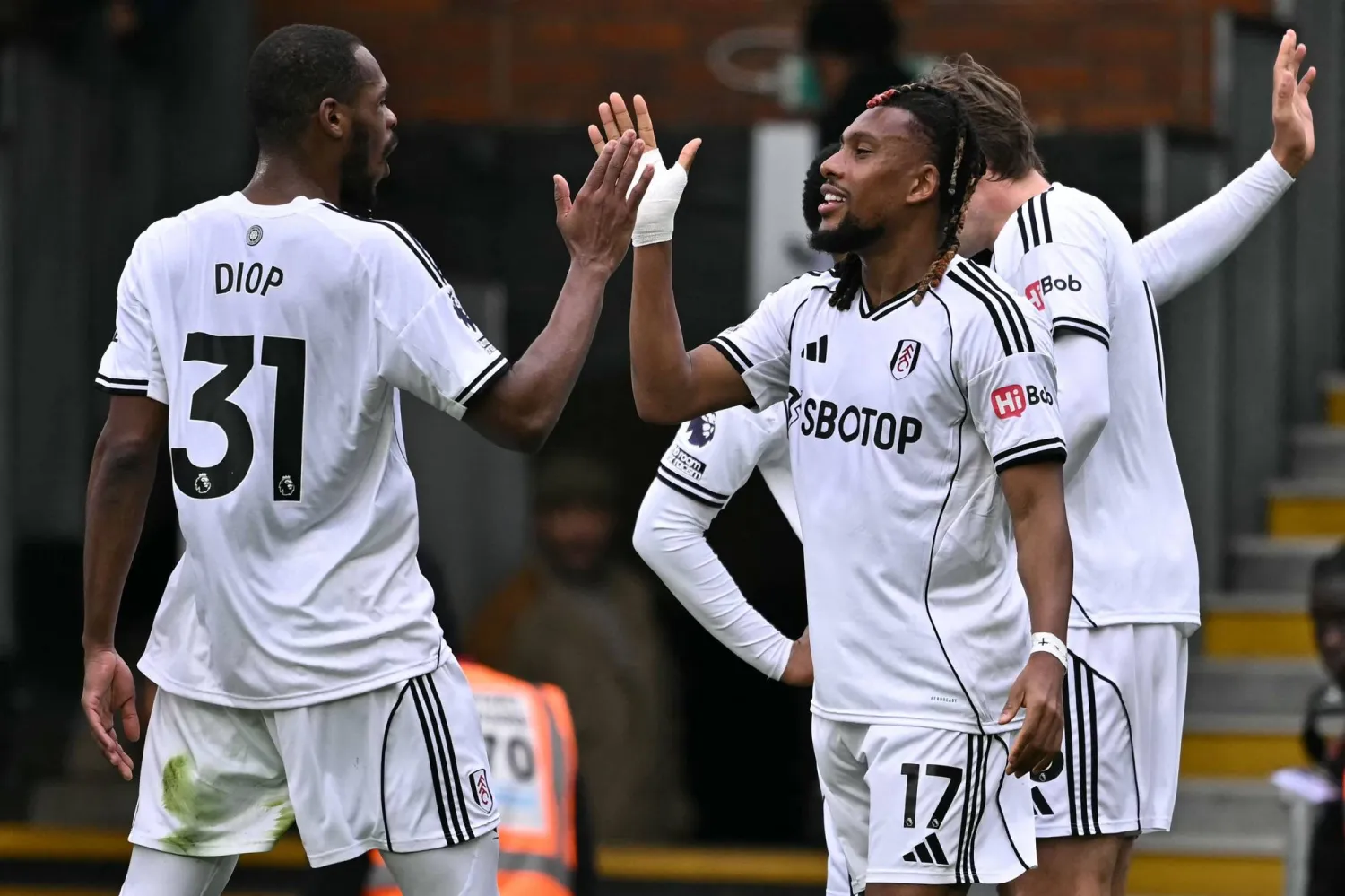 أليكس إيوبي نجم وسط فولهام «يمين» يتلقى تهنئية زميله ديوب (أ.ف.ب)