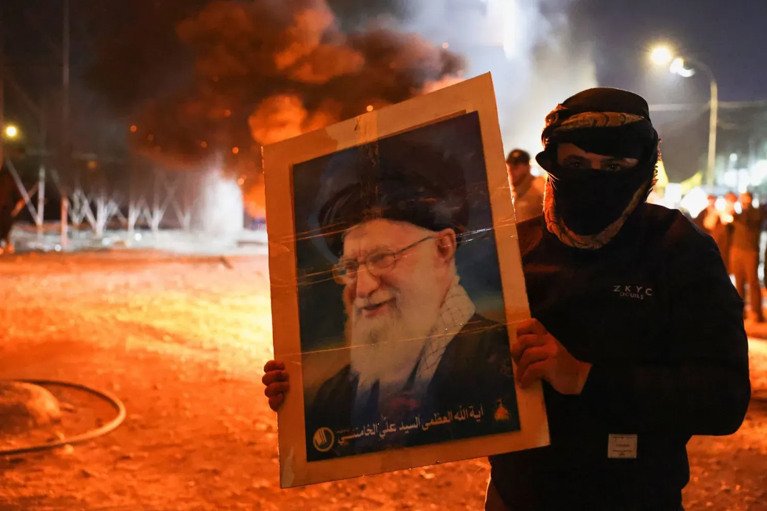 Bağdat'ta bir protestocu, İran Yüksek Lideri Ali Hamaney'in ölümünün açıklanmasının ardından onun fotoğrafını taşıyor, (Reuters)