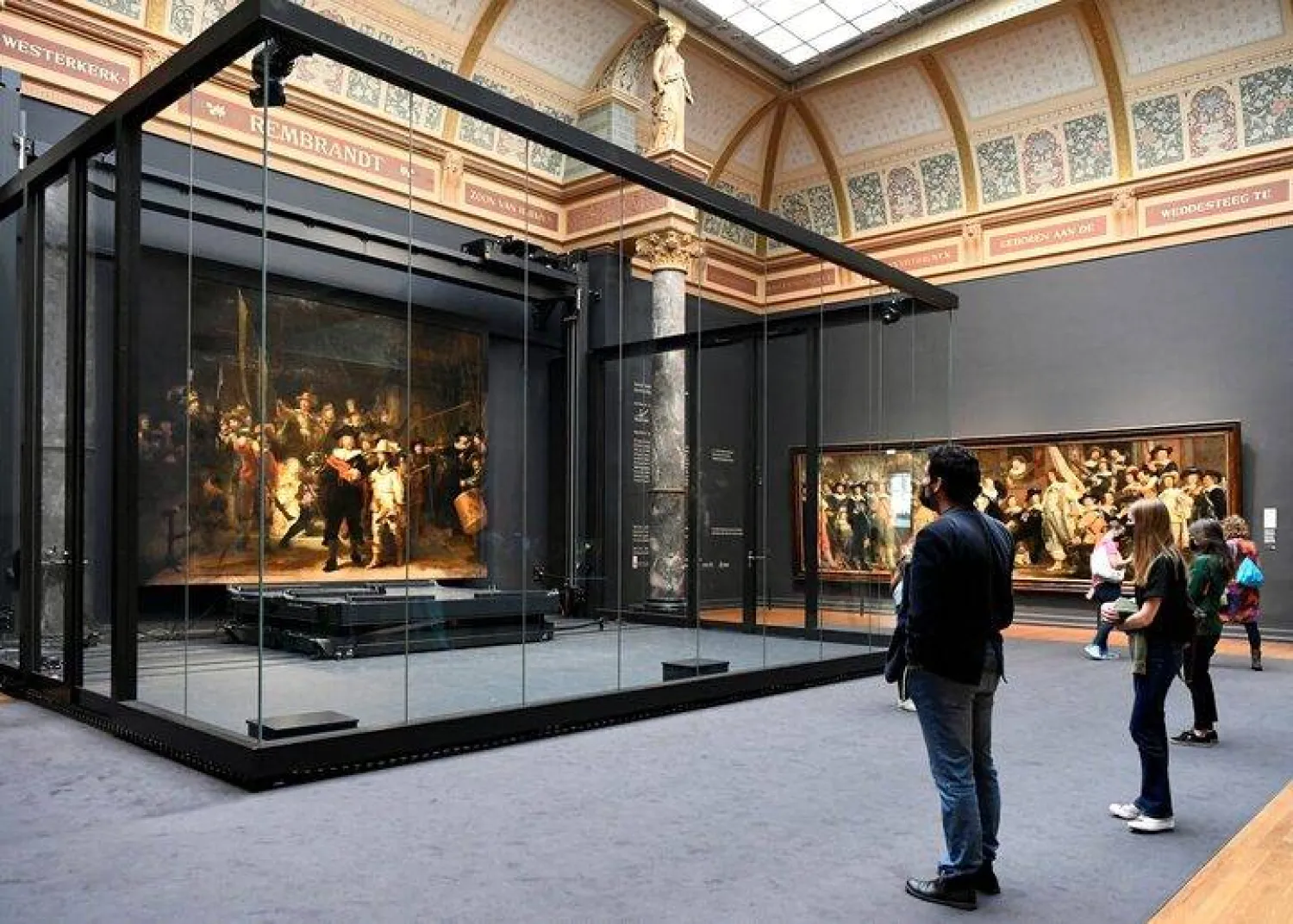 Poeple look at Rembrandt's famed Night Watch, which is back on display in what researchers say in its original size, with missing parts temporarily restored in an exhibition aided by artificial intelligence, at Rijksmuseum in Amsterdam, Netherlands June 23, 2021. REUTERS/Piroschka van de Wouw/File Photo