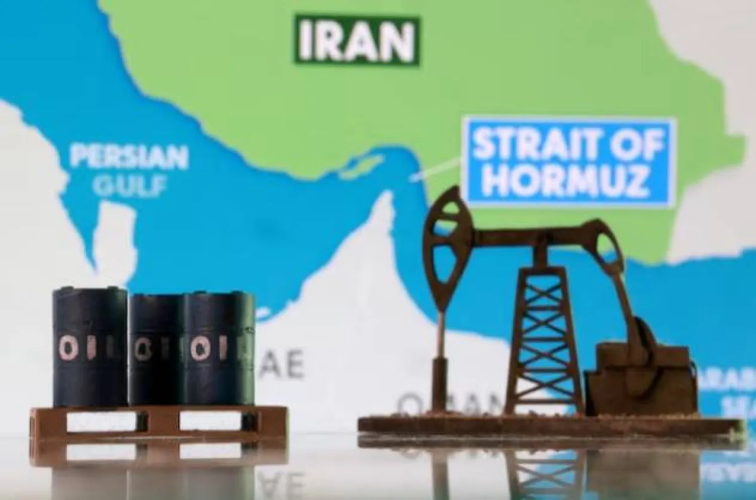 براميل نفط مطبوعة بتقنية الطباعة ثلاثية الأبعاد ومضخة نفط وخريطة تُظهر مضيق هرمز وإيران (رويترز)