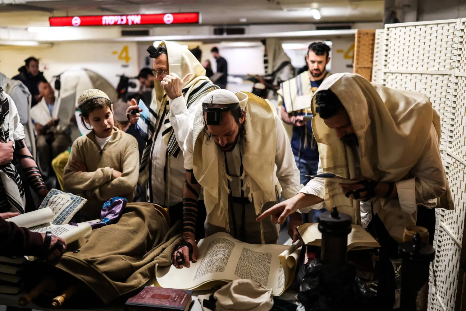 إسرائيليون يقرؤون يوم الثلاثاء من سفر ديني في موقف سيارات تحت الأرض يُستخدم كملجأ (رويترز)