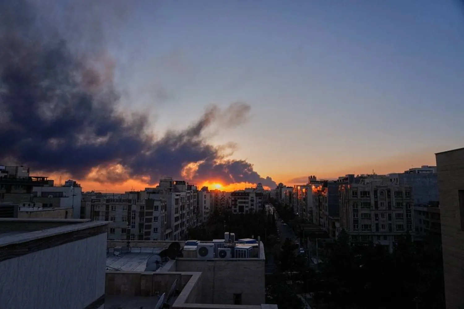  The sun sets behind a plume of smoke rising after a US–Israeli military strike in Tehran, Iran, Tuesday, March 3, 2026. (AP) 