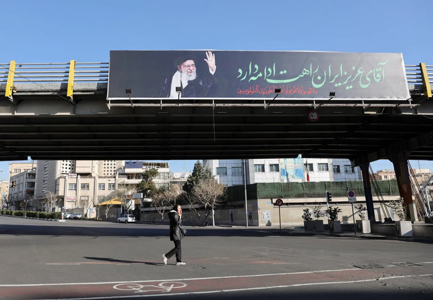 إيرانية تمر أمام لوحة عليها صورة المرشد علي خامنئي في أحد شوارع طهران (رويترز)