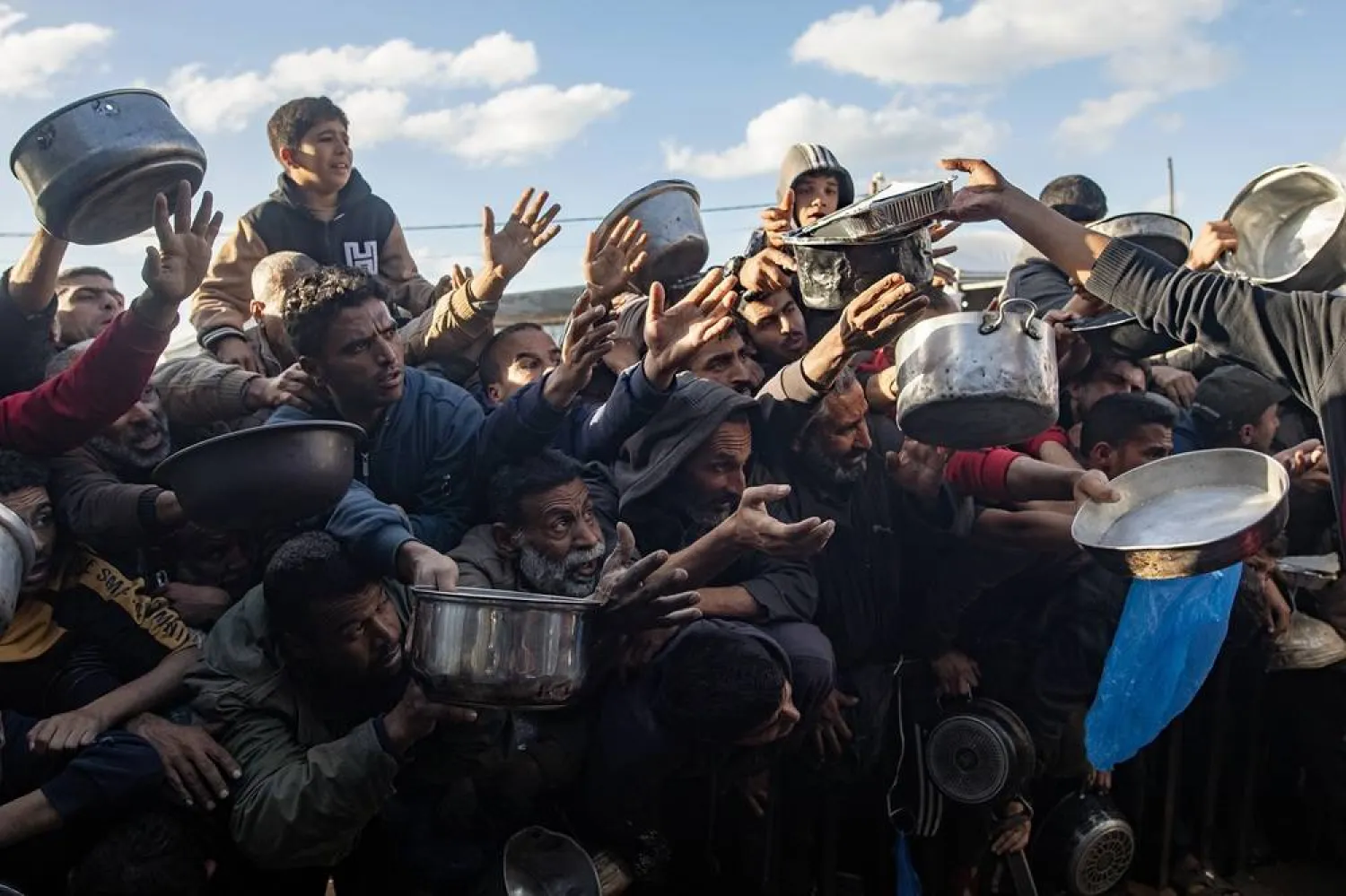 Internally displaced Palestinians scramble for an Iftar meal being distributed by a charity kitchen during the holy month of Ramadan, in Khan Younis, southern Gaza Strip, 26 February 2026. (EPA)