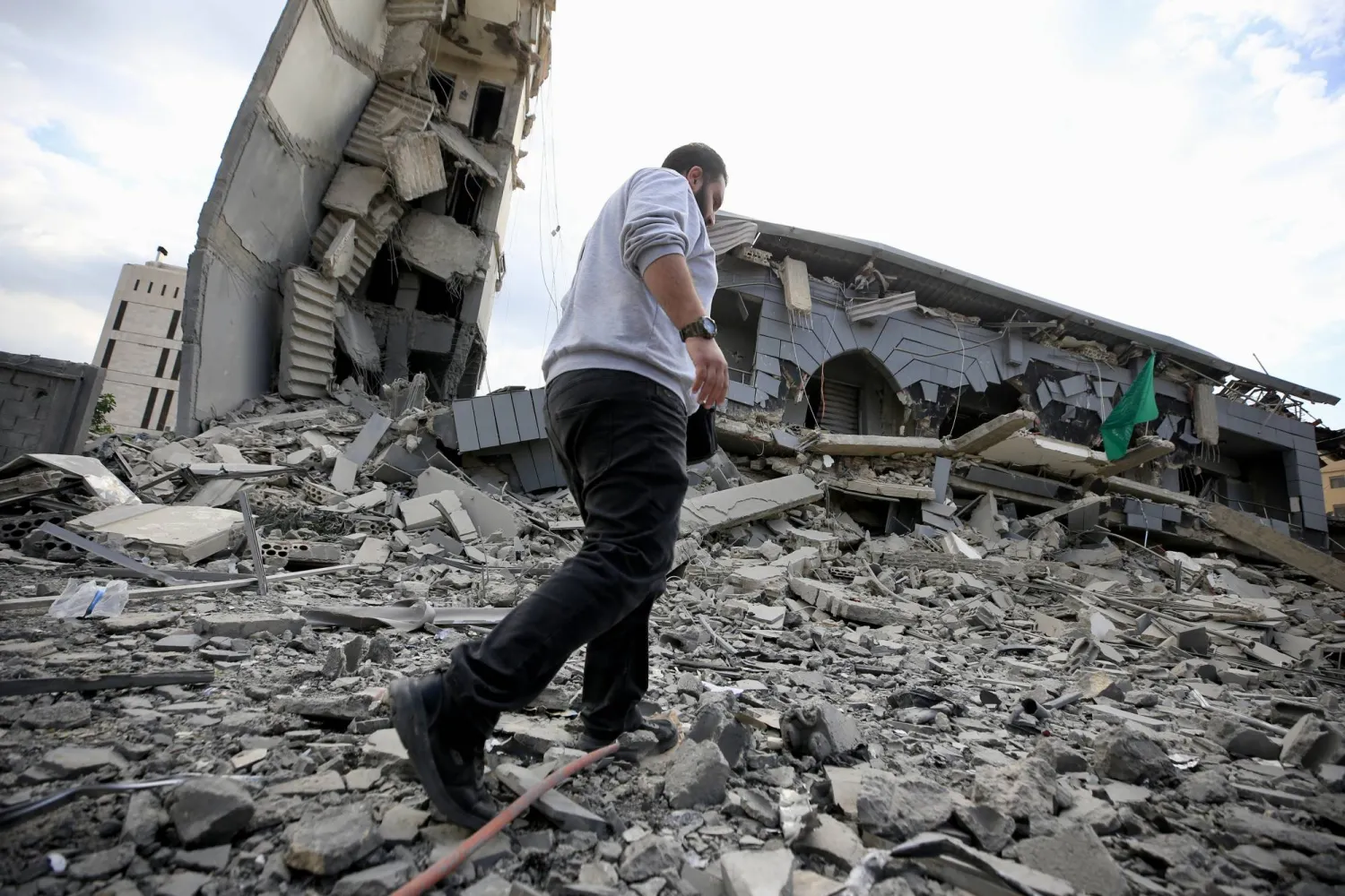 أحد السكان يتفقد ركام مبنى «الجماعة الإسلامية» الذي دمرته إسرائيل في مدينة صيدا الثلاثاء (إ.ب.أ)