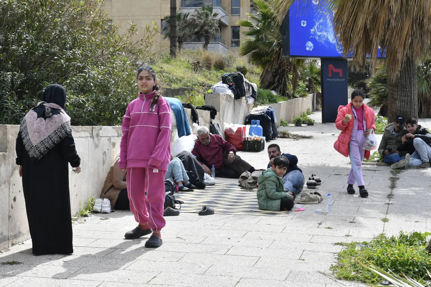 يجلس سكان نازحون على الأرض في بيروت بعد فرارهم من منازلهم بجنوب لبنان وضاحية بيروت الجنوبية (إ.ب.أ)