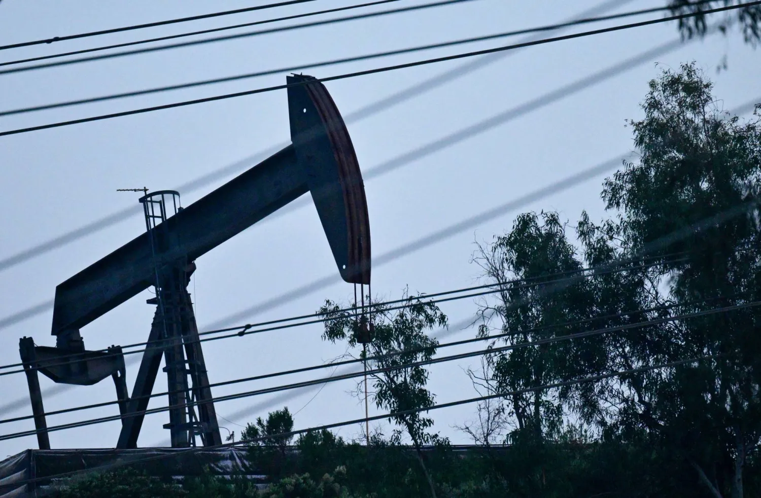 مضخة نفط تعمل في حقل مونتيبيلو النفطي خلف صف من خطوط الكهرباء في مونتيبيلو، كاليفورنيا (أ.ف.ب)