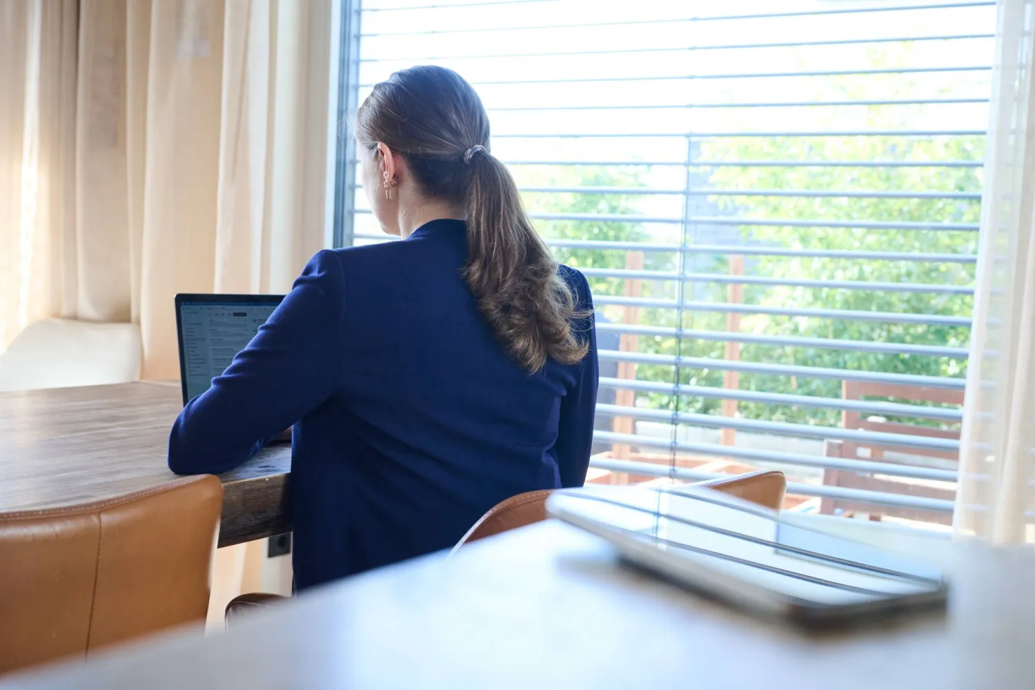 سيدة تعمل على جهاز كمبيوتر وبجوارها هاتف جوال (أرشيفية-د.ب.أ)