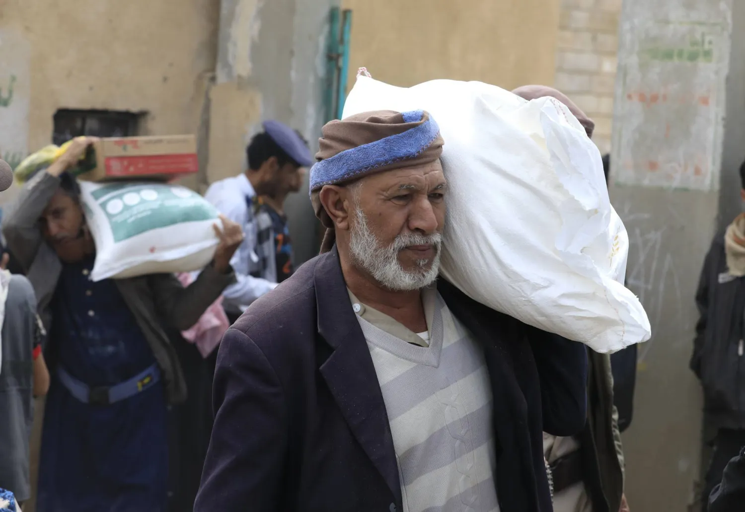 رجل يحمل جوال مساعدات غذائية في منطقة بغرب اليمن (إ.ب.أ)