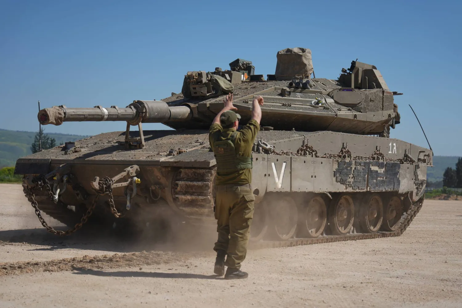 جندي إسرائيلي يوجه دبابة أثناء تعزيزات عسكرية في منطقة محاذية مع جنوب لبنان (أ.ب)