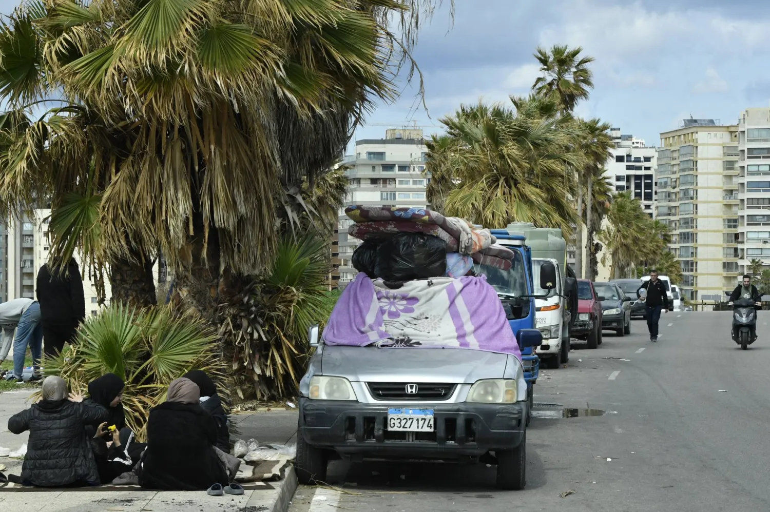 نازحون يجلسون بجوار ممتلكاتهم على رصيف في بيروت 4 مارس 2026 بعد فرارهم من جنوب لبنان والضاحية الجنوبية إثر إنذارات وغارات إسرائيلية (إ.ب.أ)