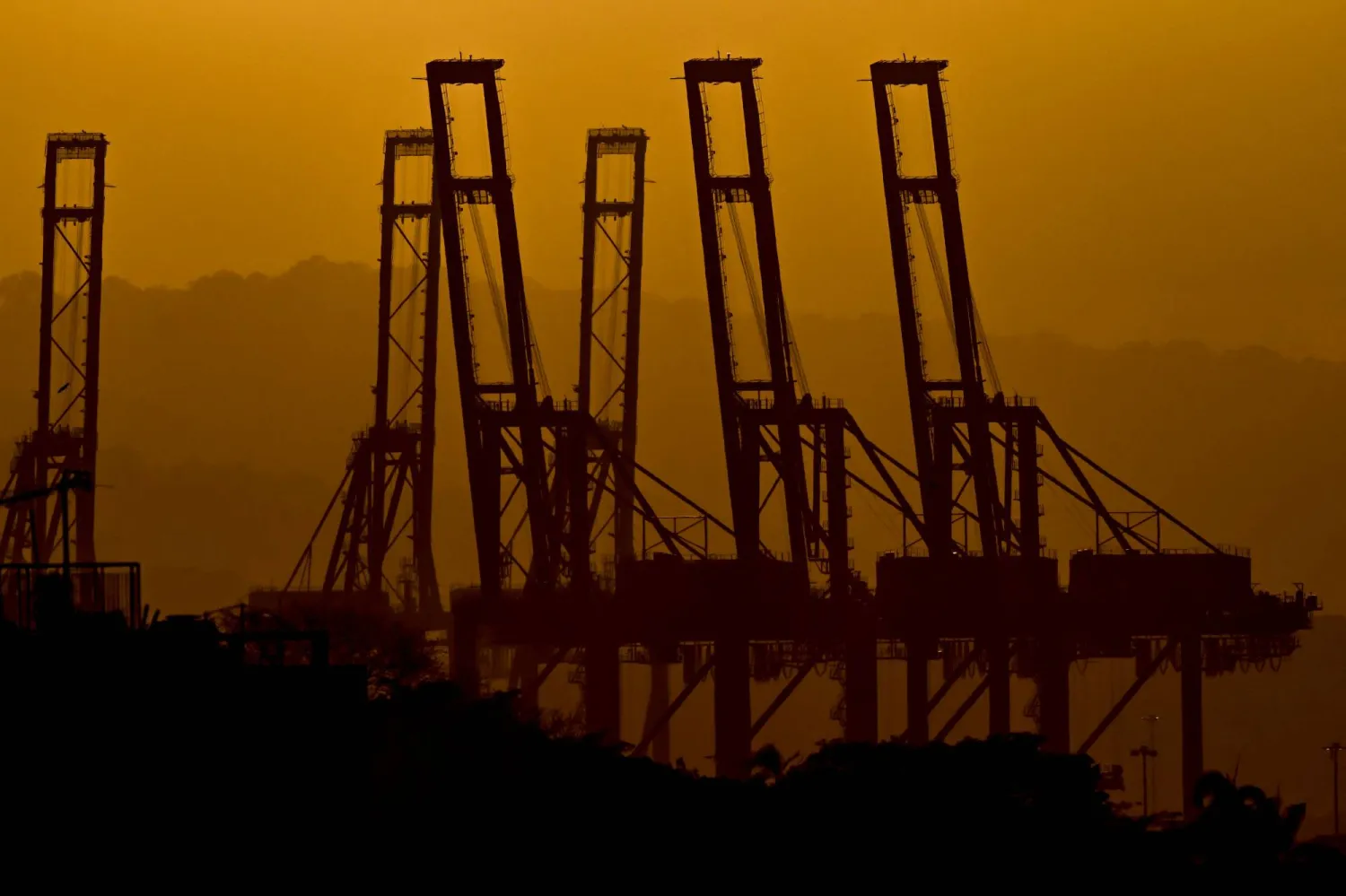 The silhouettes of the container cranes in the Port of Balboa, managed by CK Hutchison Holdings based in Hong Kong, are seen during sunset at the entrance to the Panama Canal in Panama City on February 24, 2026. (AFP)