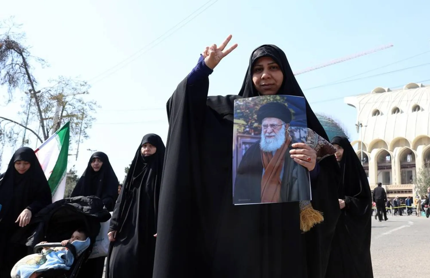 An Iranian woman flashes the victory sign while holding a picture of late Iranian supreme leader Ali Khamenei as she arrives to attend the Friday prayer ceremony at Mosallah mosque in Tehran, Iran, 06 March 2026. (EPA)
