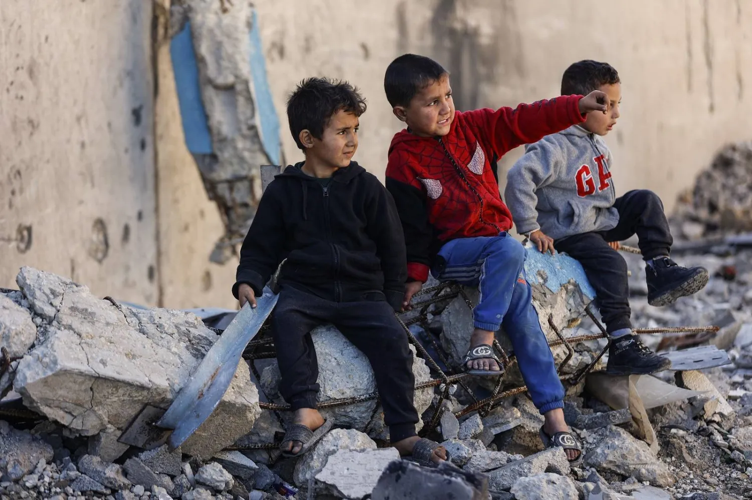 أطفال نازحون يجلسون على أنقاض مبنى مدمر في مدينة غزة (أ.ف.ب)