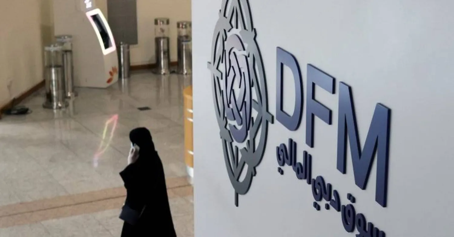 امرأة تسير بجانب شعار سوق دبي المالية (رويترز)