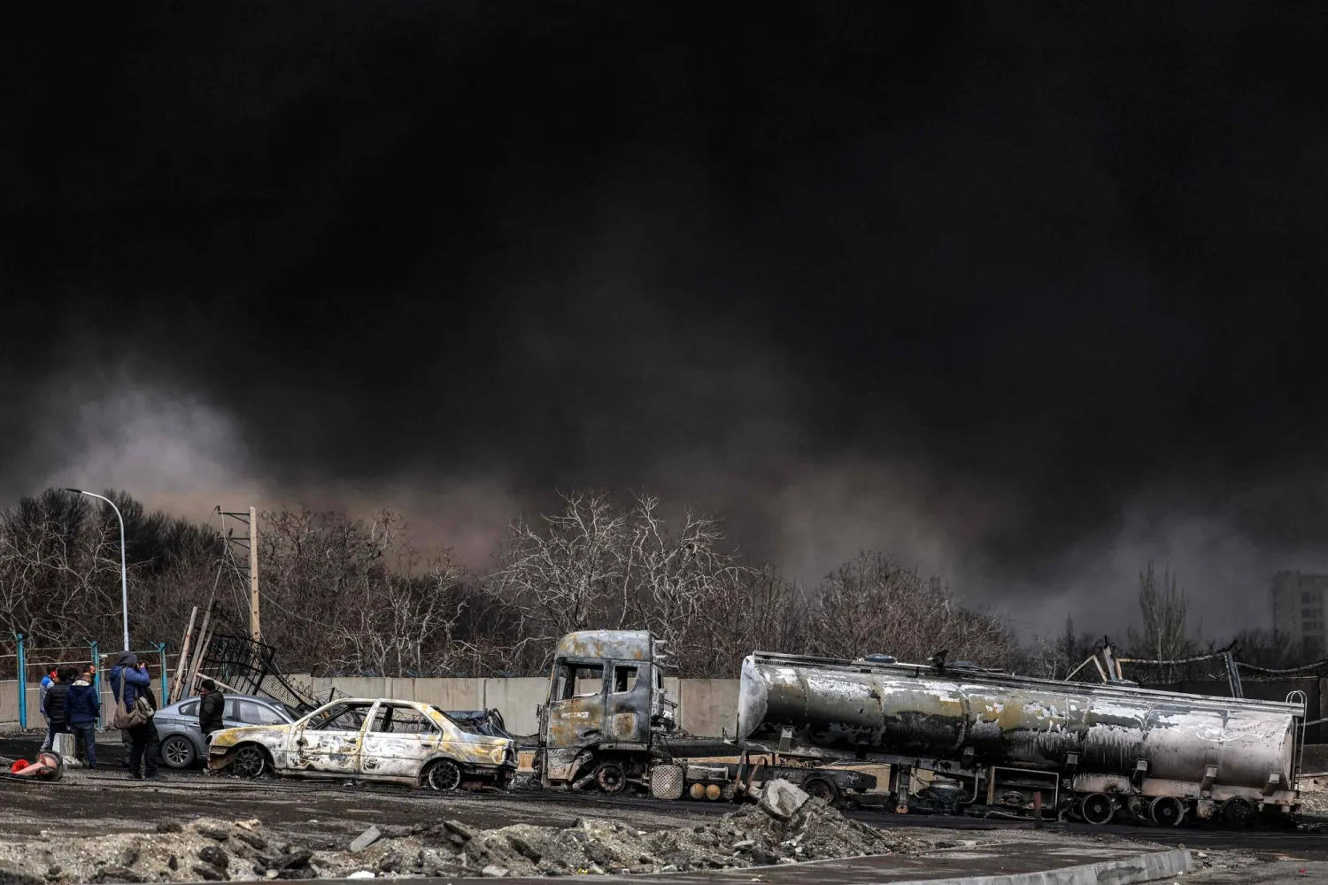 A dark smoke cloud engulfs destroyed vehicles near an ongoing fire following an overnight airstrike on the Shahran oil refinery in northwestern Tehran on March 8, 2026. (AFP)