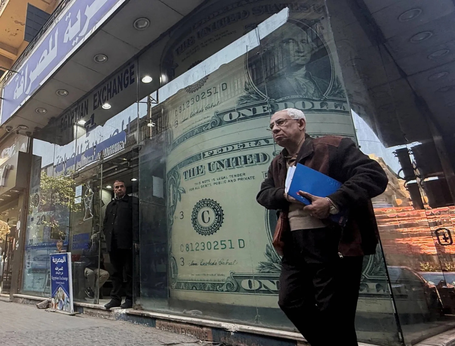 رجل مصري يمر أمام شاشة عرض لعملة الدولار الأميركي (رويترز)