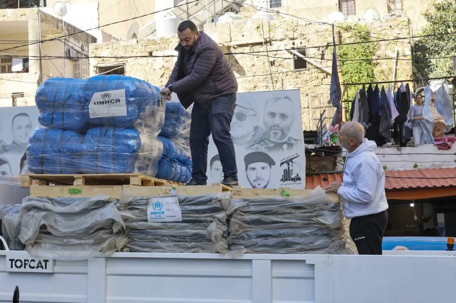 Blankets are distributed at a school converted into a shelter in Beirut, where a banner displaying images of leaders and members of Hezbollah can be seen (EPA). 