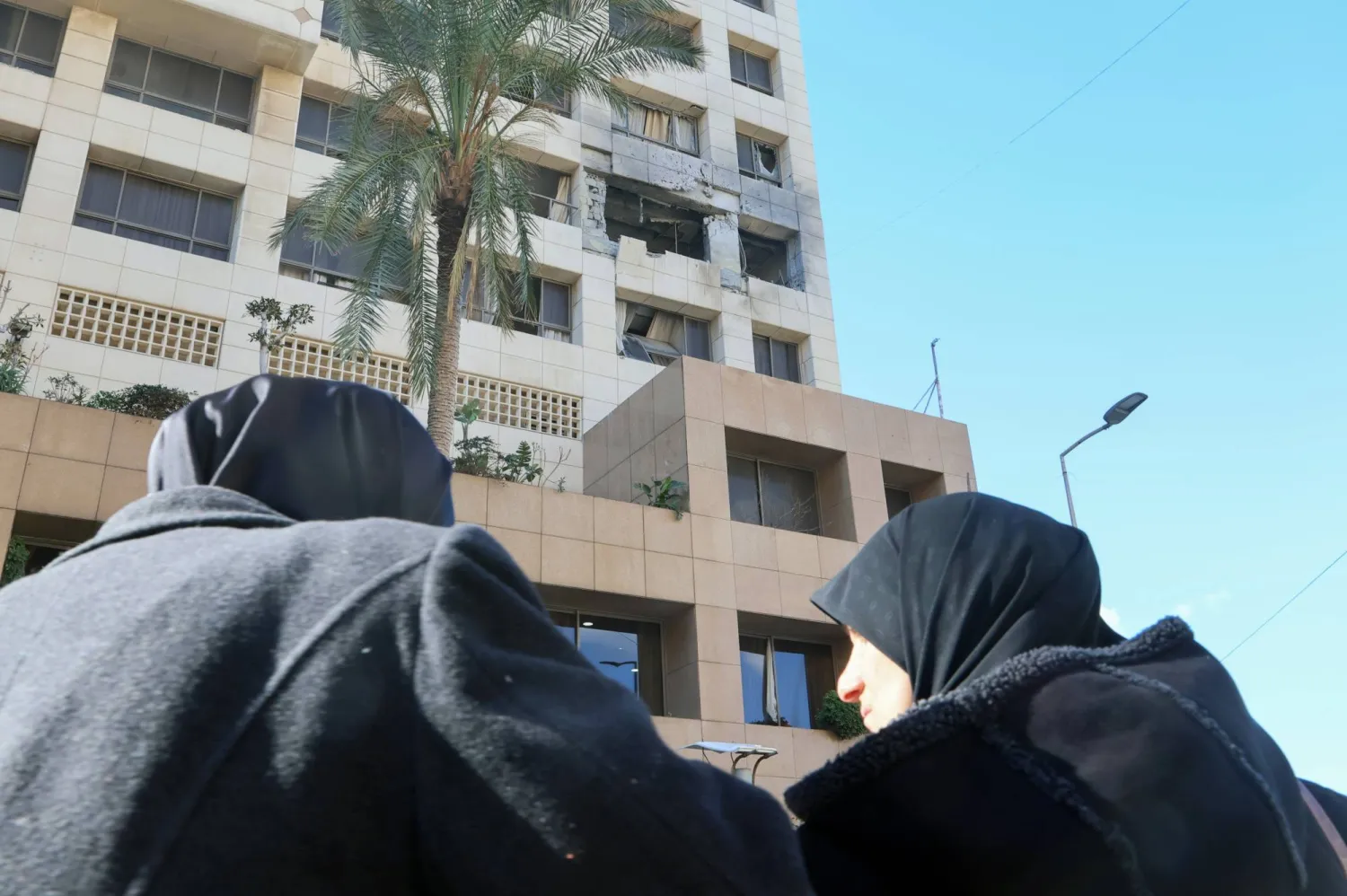 لبنانيتان تقفان أمام مدخل فندق «رامادا» بمنطقة الروشة غداة استهداف إسرائيلي لغرفتين في الفندق أسفر عن مقتل 4 أشخاص وإصابة 10 آخرين (إ.ب.أ)