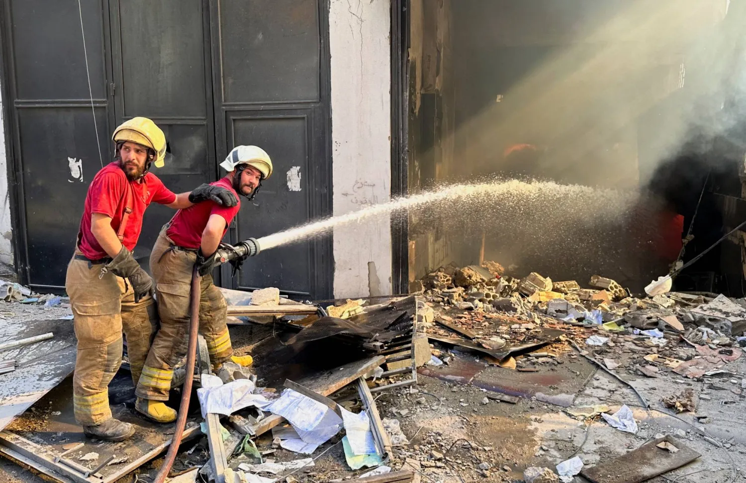 عناصر من الدفاع المدني يحاولون إخماد نيران اشتعلت في مبنى استهدفته غارة إسرائيلية في ضاحية بيروت الجنوبية (رويترز)