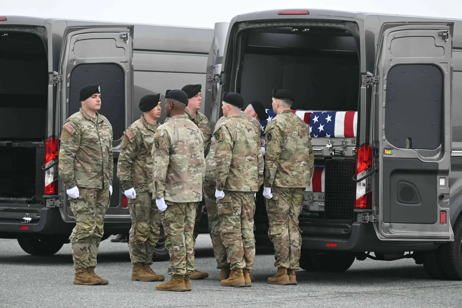 فريق من الجيش الأميركي يقف أمام صناديق نقل رفات الجنود المغطاة بالأعلام خلال مراسم رسمية في ديلاوير (أ.ف.ب)