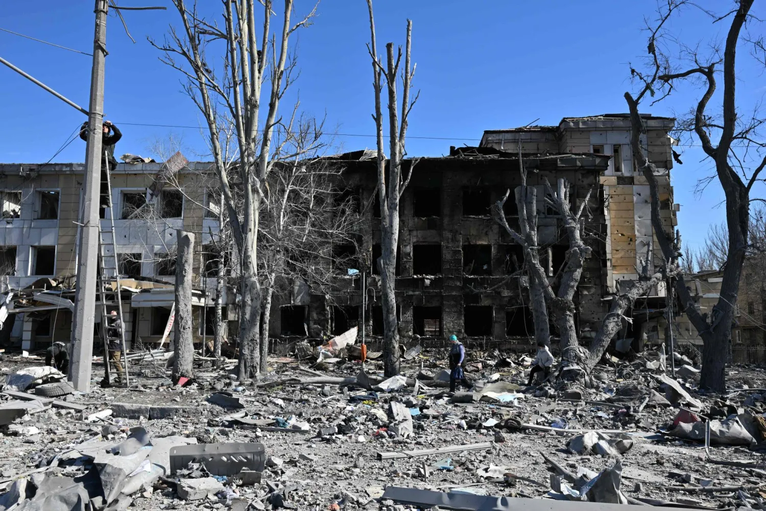 عمال يصلحون الأسلاك أمام عيادة أطفال متضررة في أعقاب قصف حديث وصفه مسؤولون بأنه ضربة عسكرية أوكرانية في دونيتسك الخاضعة للسيطرة الروسية (أ.ف.ب)