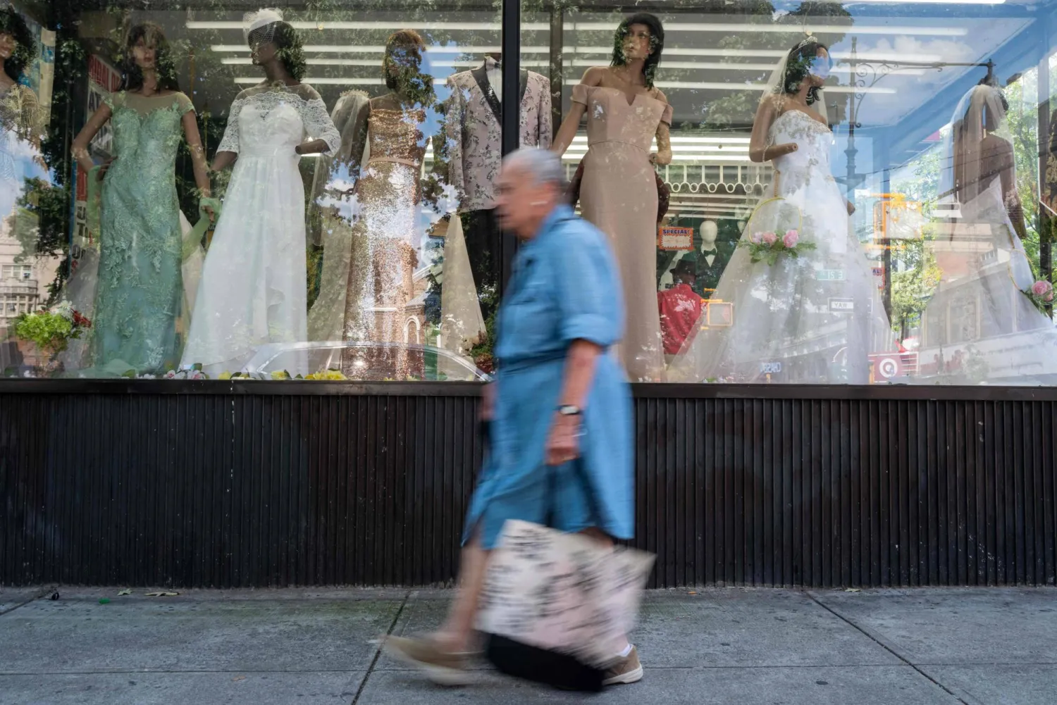 امرأة تمر أمام واجهة متجر تعرض فساتين في بروكلين (أ.ف.ب)