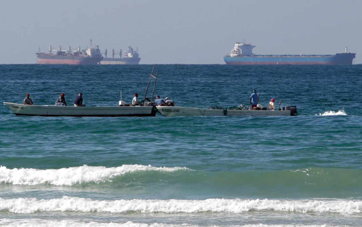 Fishermen work in front of oil tankers south of the Strait of Hormuz Jan. 19, 2012, offshore the town of Ras Al Khaimah in United Arab Emirates. (AP Photo/Kamran Jebreili, File)