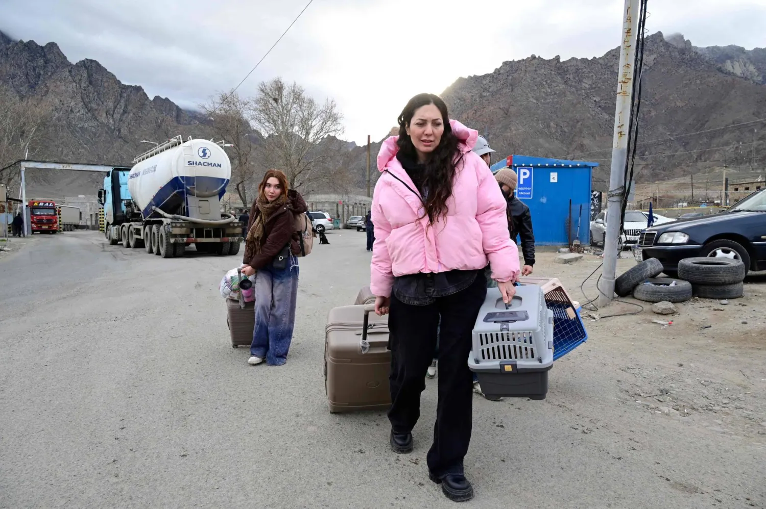 لاجئون يسيرون حاملين أمتعتهم بعد عبورهم الحدود من إيران إلى أرمينيا عند نقطة تفتيش حدودية في بلدة ميغري جنوب أرمينيا، 8 مارس 2026 (أ.ف.ب)