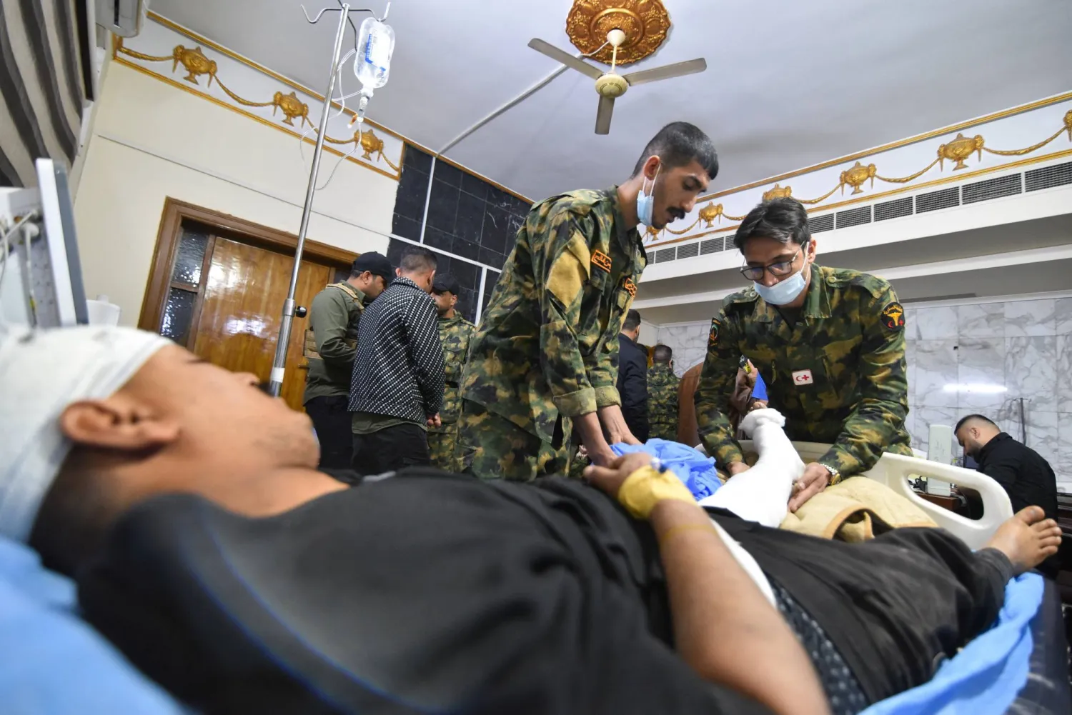 عناصر من «الحشد الشعبي» يعالجون زميلاً لهم جُرح في قصف استهدف أحد مقارهم جنوب الموصل (رويترز)